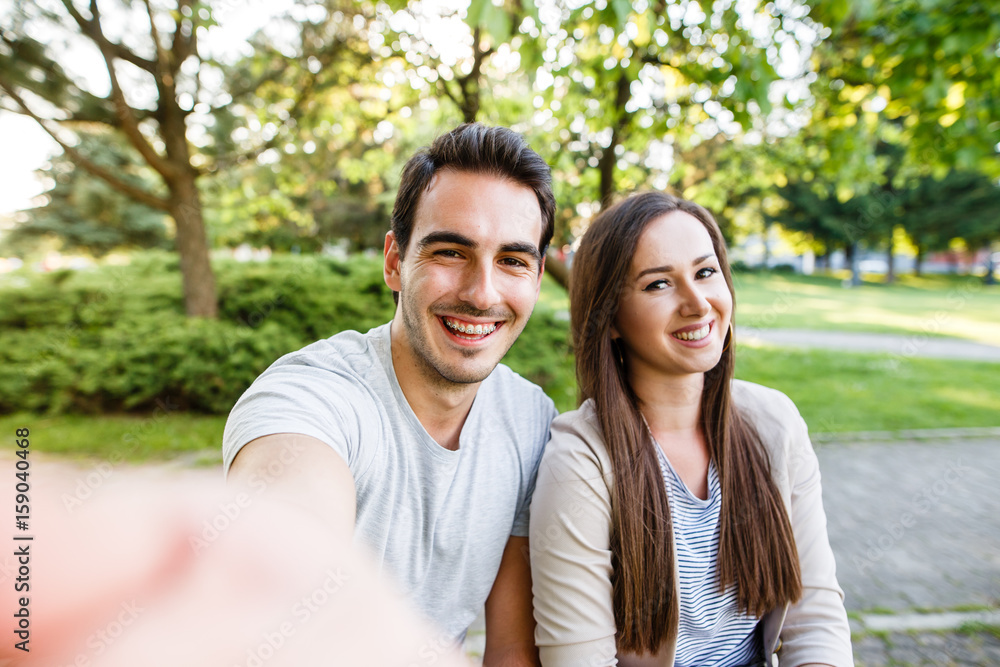 Cute and happy couple enjoying in park and taking selfie