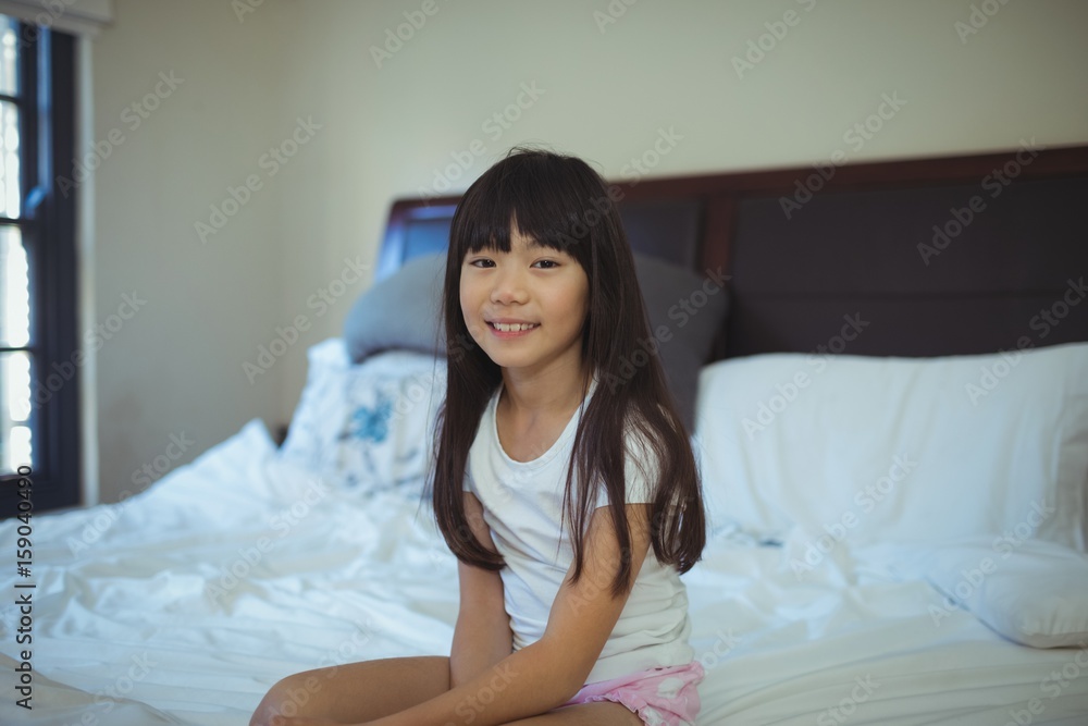Smiling girl sitting on bed in the bed room Smiling girl sitting on bed in the bed room
