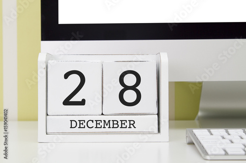 Cube shape calendar for DECEMBER 28 and computer keyboard on table. 