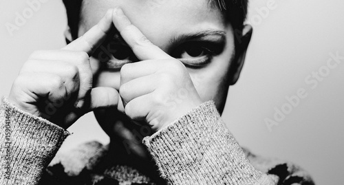 Boy making triangle shape over his eye photo