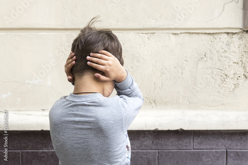 Young boy closes ears with hands. Behavior, attitude concept