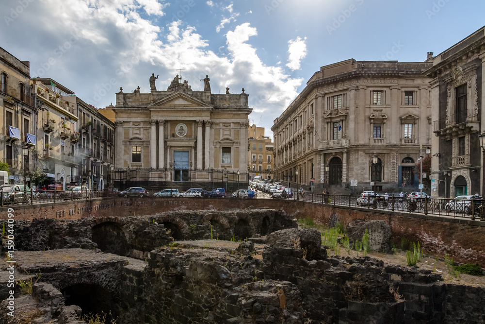 Ruins of the Roman Amphitheater at the Stesicoro Square with San Biagio Church on background - Catania, Sicily, Italy