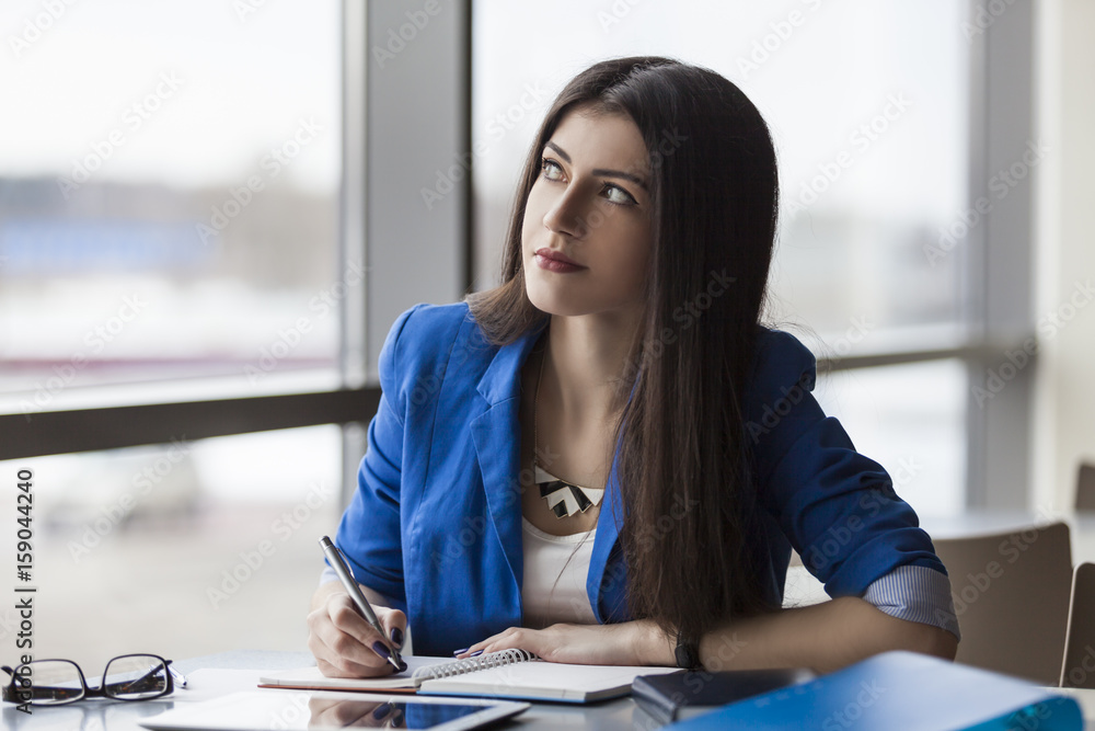 Obraz premium Pensive businesswoman writing in notebook