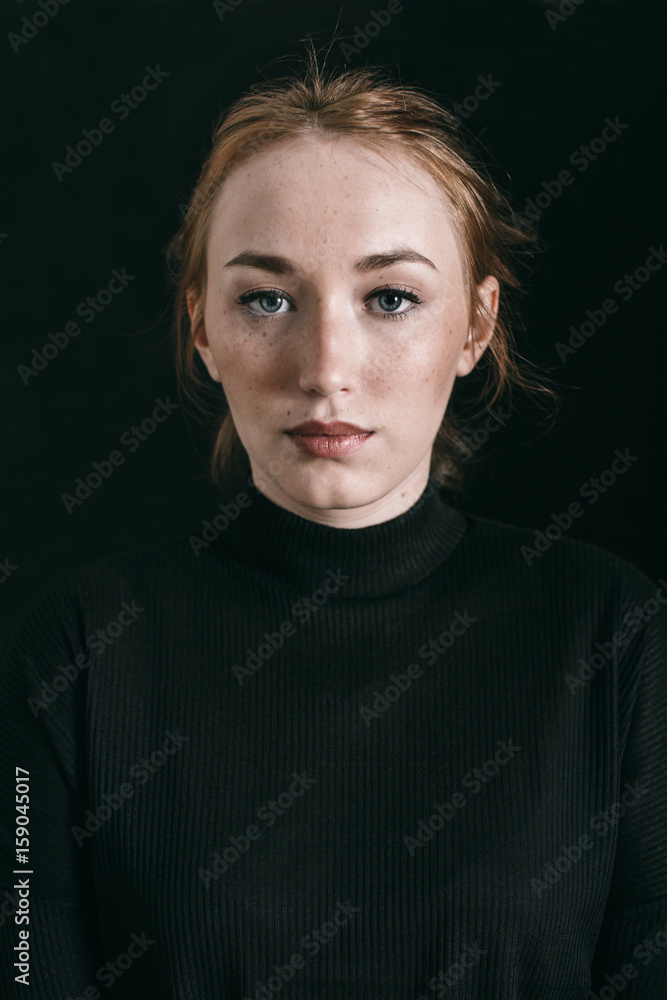 Closeup portrait of a ginger freckled woman on black Closeup portrait of a ginger freckled woman on black