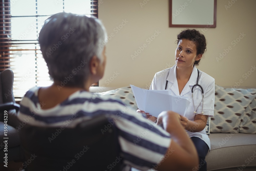 Female doctor interacting with senior woman on wheelchair Female doctor interacting with senior woman on wheelchair