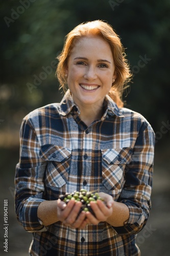 Smiling female holding olives at farm
