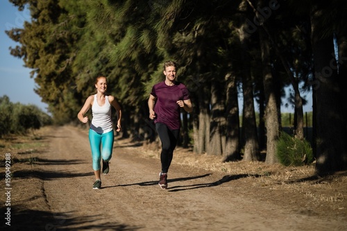 Full length of young couple jogging at farm