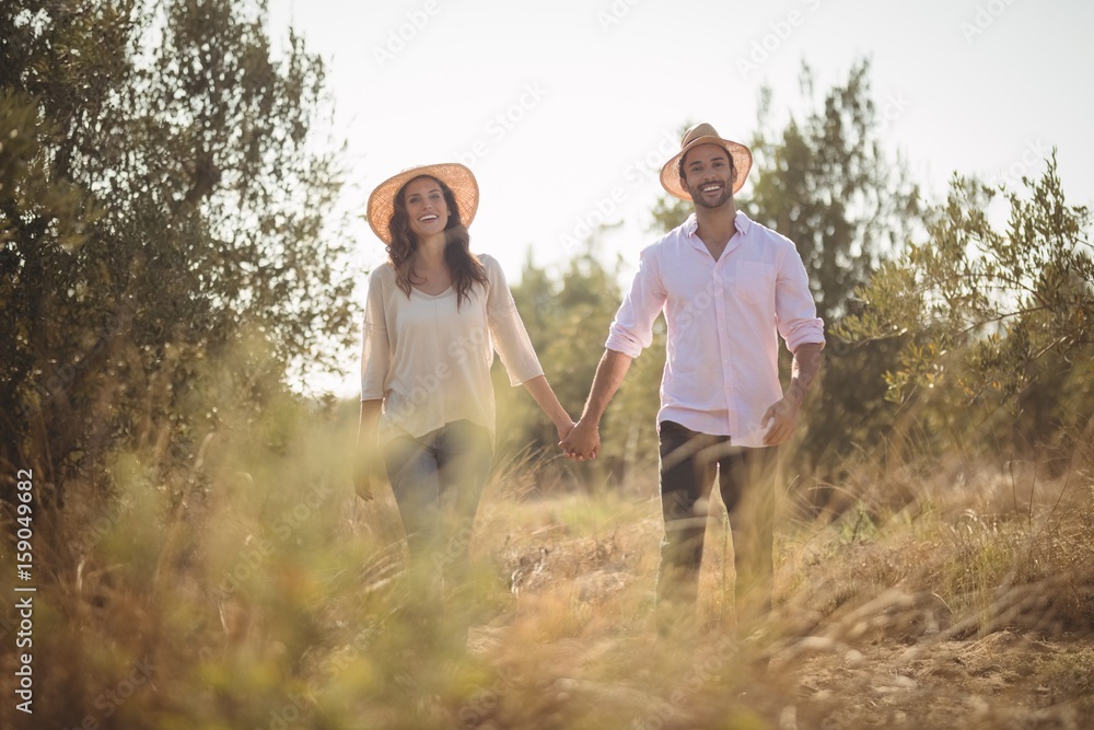 Smiling young couple holding hands at farm