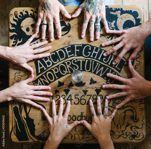 Seance hands joined on a Ouija board