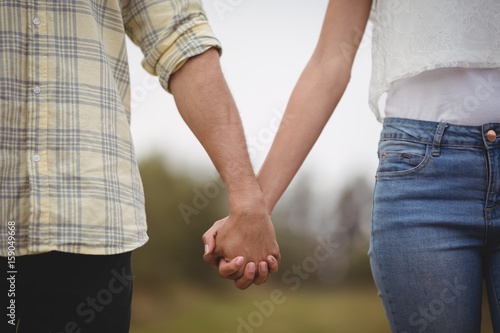 Mid section of couple holding hands at farm