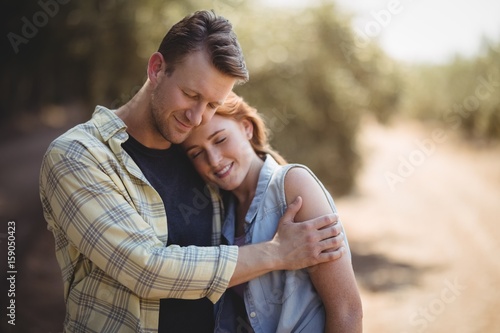 Smiling couple embracing on field at olive farm