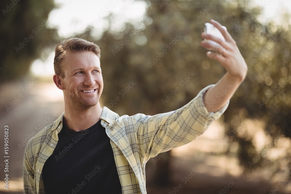 Smiling man taking selfie at olive farm Smiling man taking selfie at olive farm