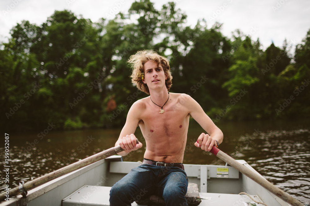 A young boy rows his boat on a calm lake A young boy rows his boat on a calm lake