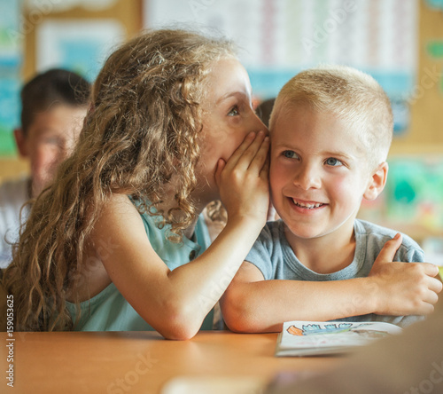 Girl Whispering Something to Her Classmate