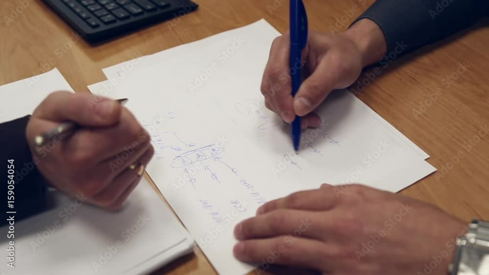 A man draws a block diagram on a sheet of paper, there is a discussion A man draws a block diagram on a sheet of paper, there is a discussion