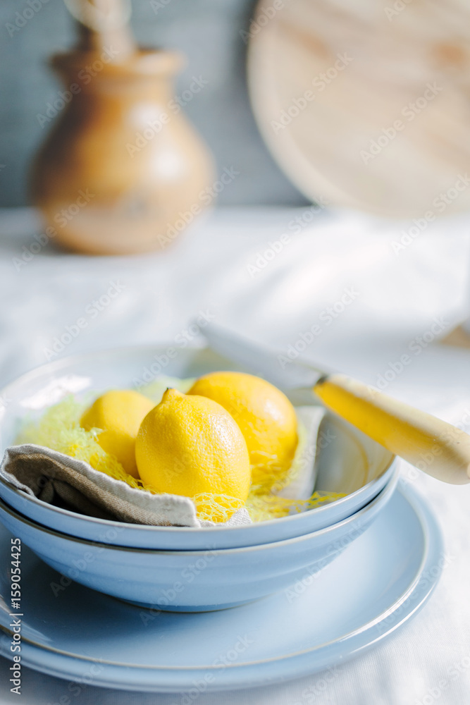 Three lemons in a blue bowl on a table Three lemons in a blue bowl on a table