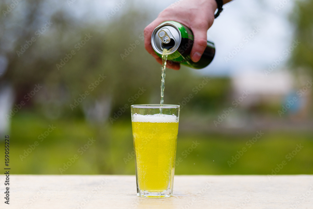 An energy drink is poured from the jar into a glass on a wooden table.  Stock Photo | Adobe Stock