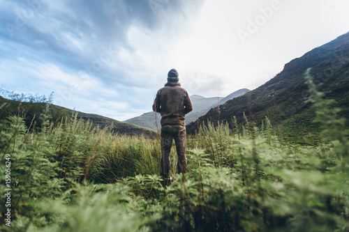 hiker outdoorsman standing in a mountain valley photo