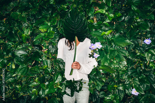 woman hiding behind a leaf against hedge