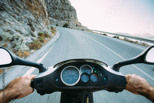 Point of view riding a moped on a winding mountain road