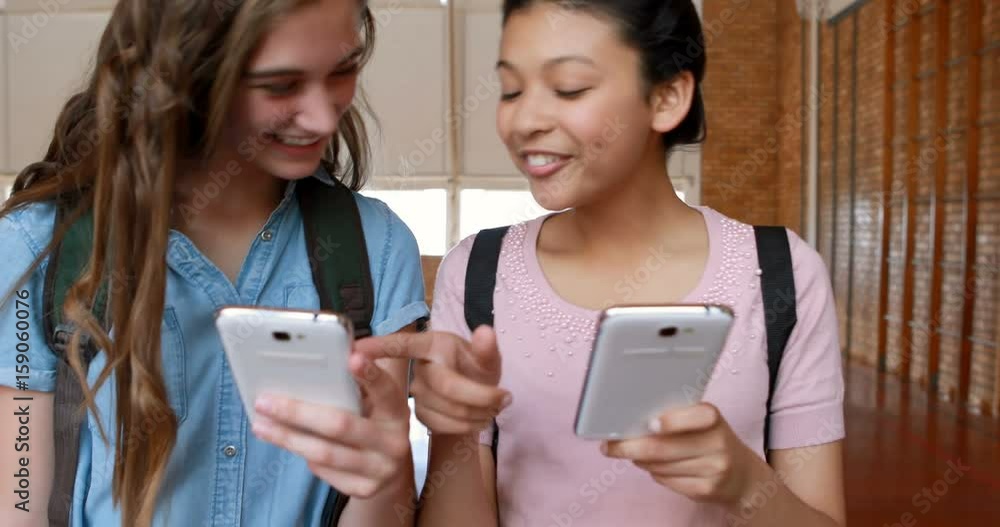 Happy schoolgirls using mobile phone in basketball court Happy schoolgirls using mobile phone in basketball court