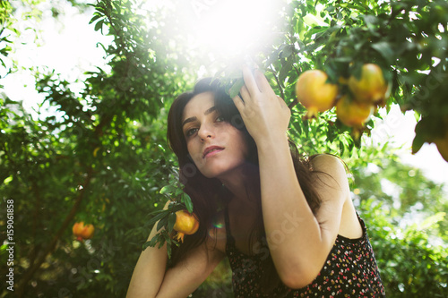 Eve like young Mediterranean woman in garden with fruit