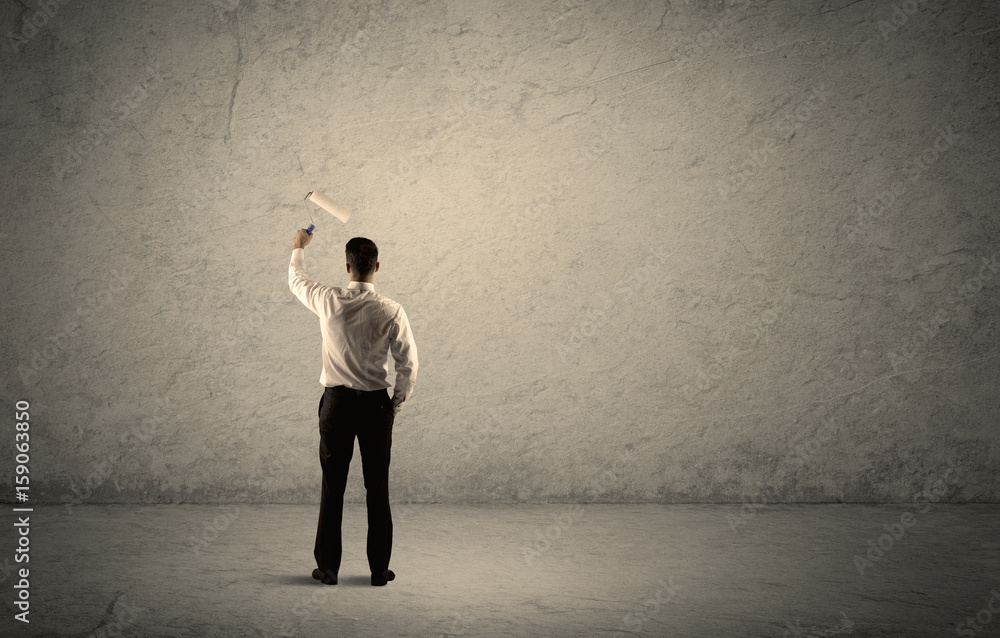 Salesman with roller standing at empty wall Salesman with roller standing at empty wall