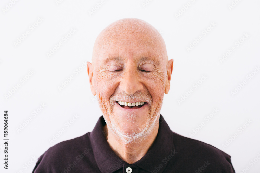 Portrait of an elderly man laughing with eyes closed over white Portrait of an elderly man laughing with eyes closed over white