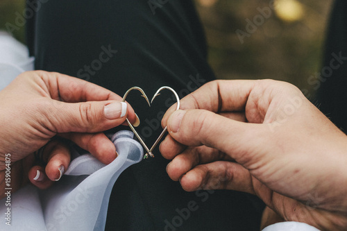 Couple holding two fish hooks in a heart shape photo