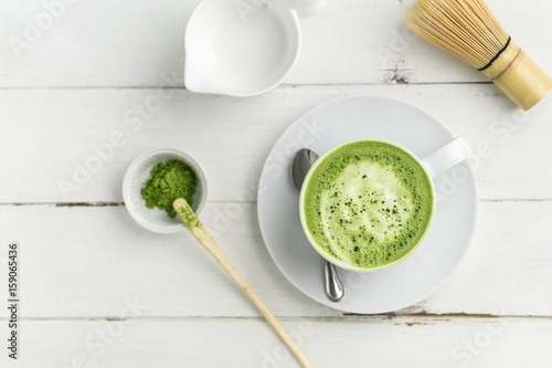 Matcha latte cup on white background top view. This latte is a delicious way to enjoy the energy boost & healthy benefits of matcha. Matcha is a powder of green tea leaves packed with antioxidants.