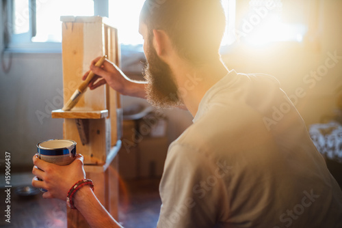 Man painting the a wooden shelf 