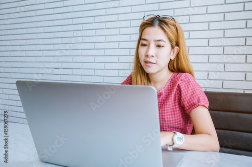 Asian girl working at a coffee shop sitting with mobile phone and laptop. Manager doing job at loft office