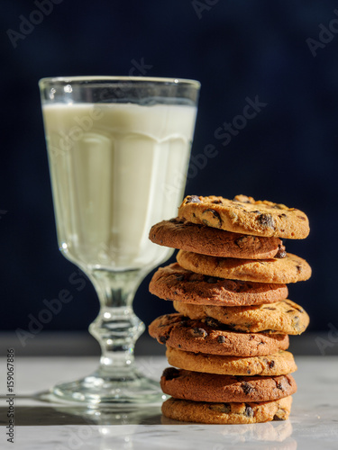 Glass of milk and cookies on stone table with dark wall background photo