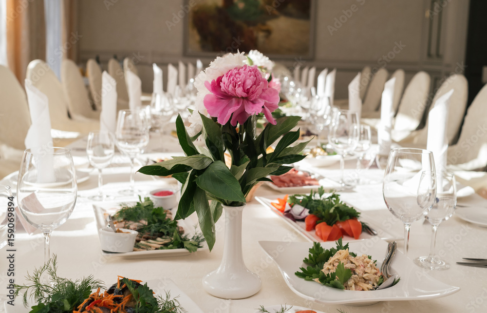 Beautiful wedding bouquet of white and pink peonies in white vase on dinner table in blur. Table setting at luxury wedding reception. Flowers on the table Beautiful wedding bouquet of white and pink peonies in white vase on dinner table in blur. Table setting at luxury wedding reception. Flowers on the table