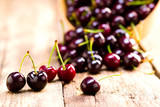 Cherry in a wooden bowl on the background of wooden boards, studio light