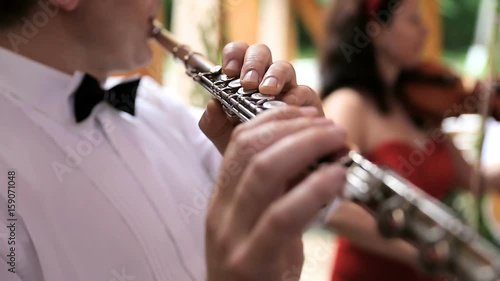 Musician plays the flute. Flutist professionally playing the flute in the wedding party photo