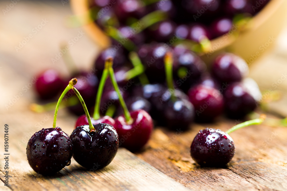 Cherry in a wooden bowl on the background of wooden boards, studio light Cherry in a wooden bowl on the background of wooden boards, studio light