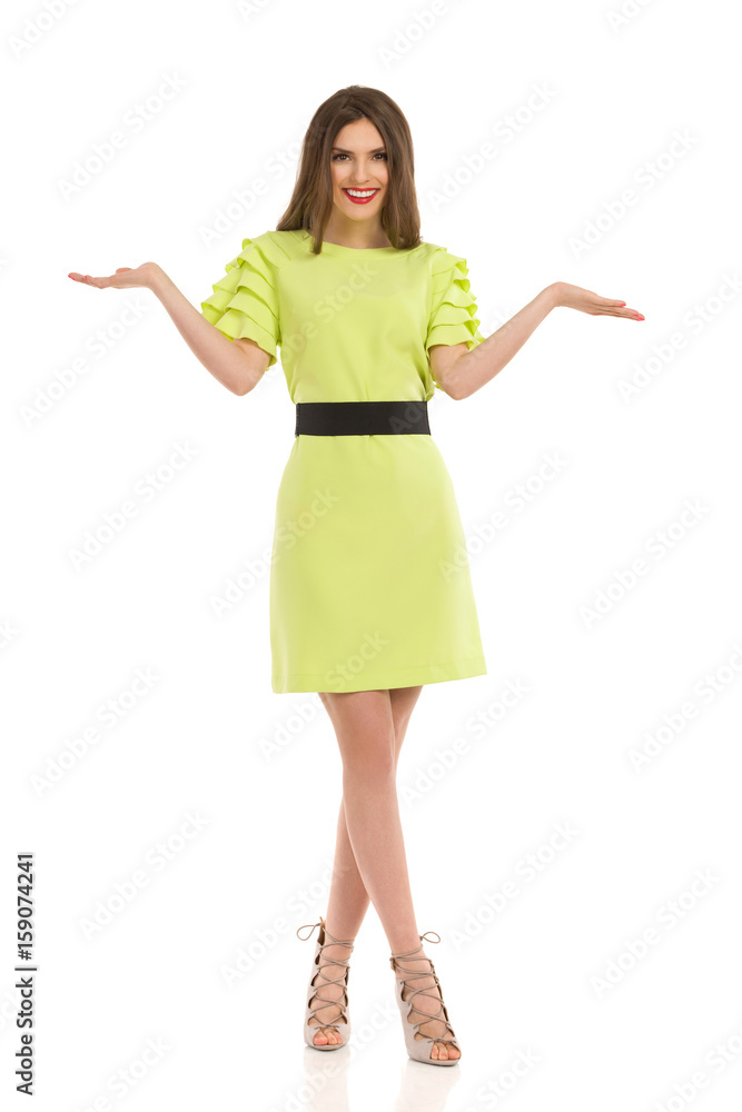 Fashion Model In Lime Green Dress Is Presenting With Hands Raised Fashion Model In Lime Green Dress Is Presenting With Hands Raised