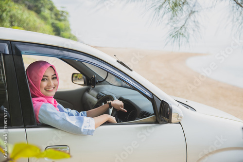 happy woman wearing hijab travelling with a car to the beach on © Odua Images