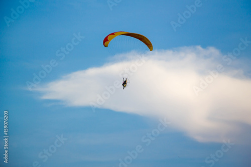 man flying with paramotor engine glider parachute on beautiful blue sky