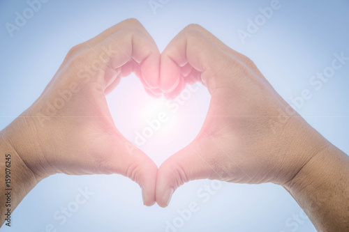 man hands in the form of heart on blue sky background with lens flare   concept of love  valentine