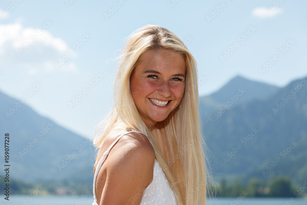 Happy young woman at a lake in the mountains