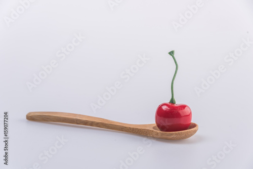 Cherry isolated on wooden spoon on white background.