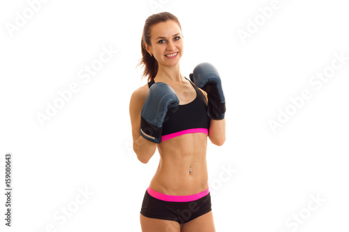 young slim athlete in short shorts and top, smiling and holding hands in front of him boxing gloves