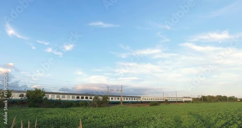 Passenger Train is passing over a green field photo