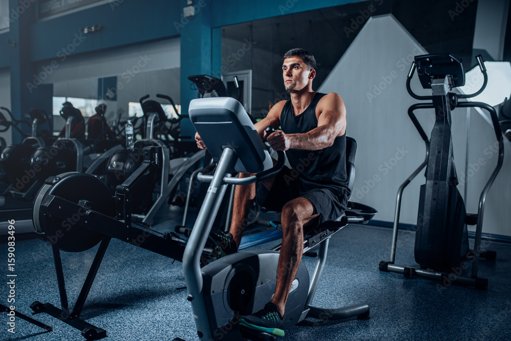 Muscular athlete training legs on exercise machine