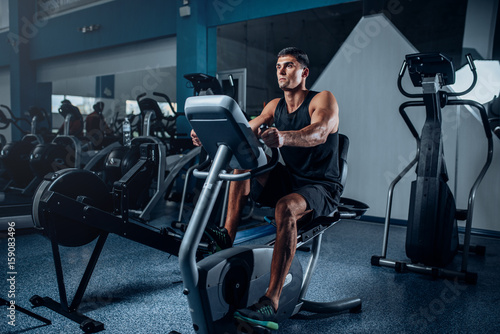 Muscular athlete training legs on exercise machine