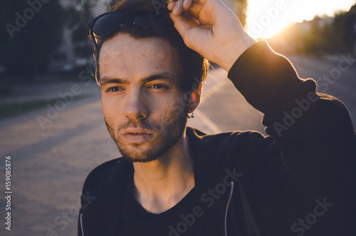 Close-up. Portrait of a stylish guy with raised glasses at sunset