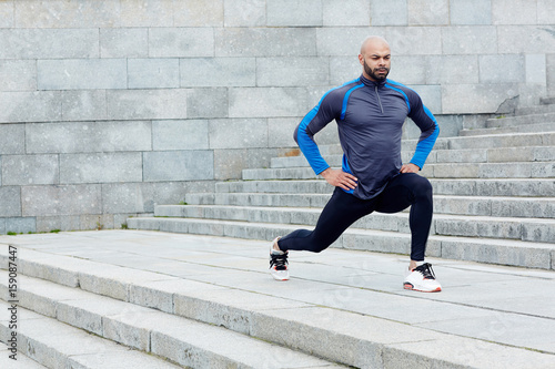 Sportive man exercising between staircases in the city