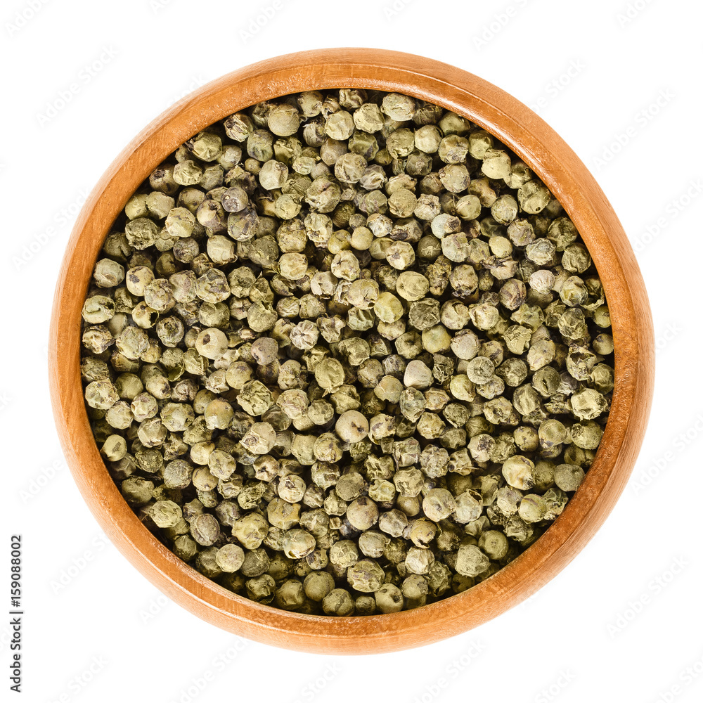 Green pepper in wooden bowl. Dried berries of Piper nigrum are called peppercorns. Made from the unripe drupes of the pepper plant. Spice and seasoning. Isolated macro food photo close up over white. Green pepper in wooden bowl. Dried berries of Piper nigrum are called peppercorns. Made from the unripe drupes of the pepper plant. Spice and seasoning. Isolated macro food photo close up over white.
